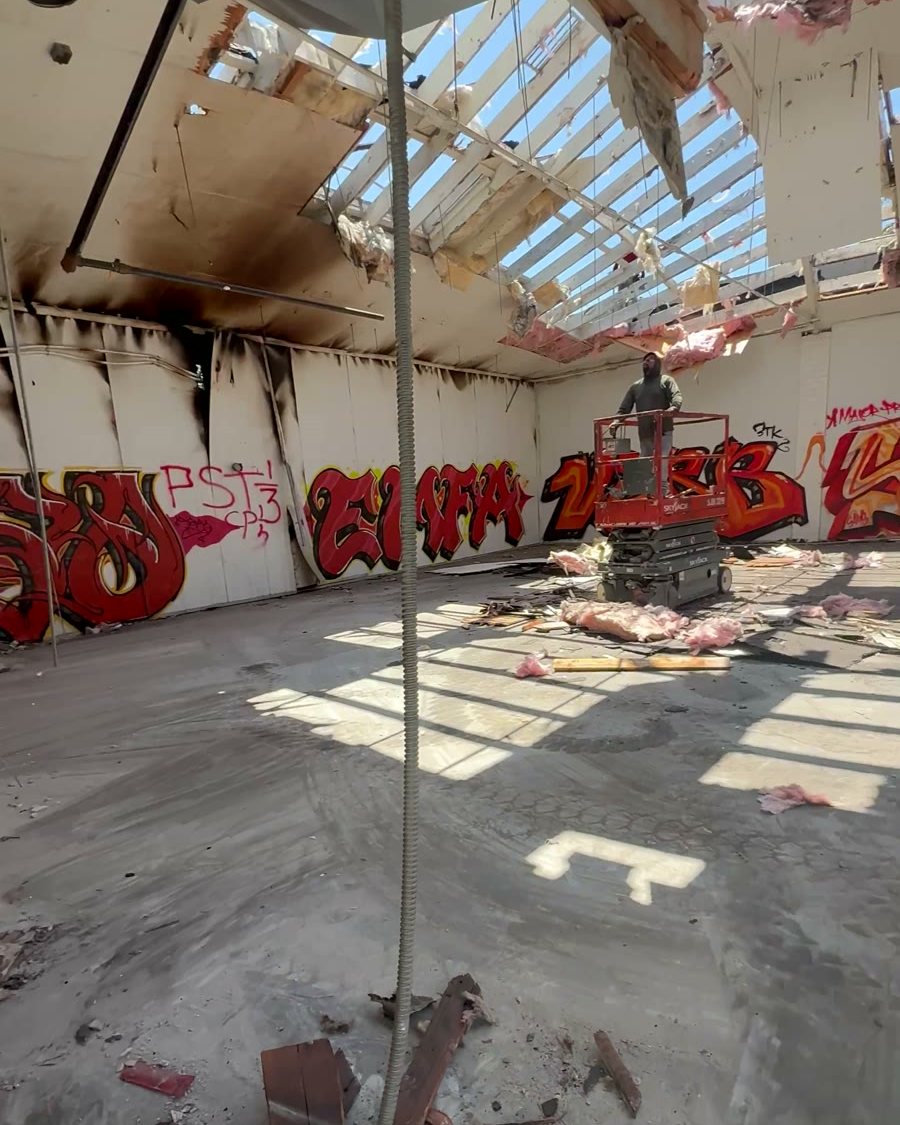 The same warehouse after the fire: roof burned open, charred walls and debris on the floor