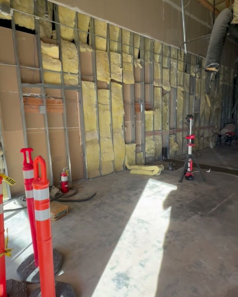 The same space before: an empty shell with bare walls and concrete floor